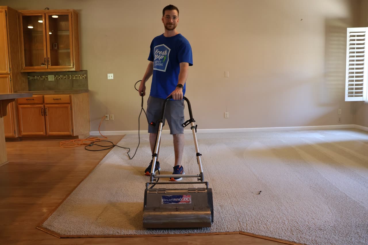 Fresh Step owner standing with a carpet brush on a living room carpet