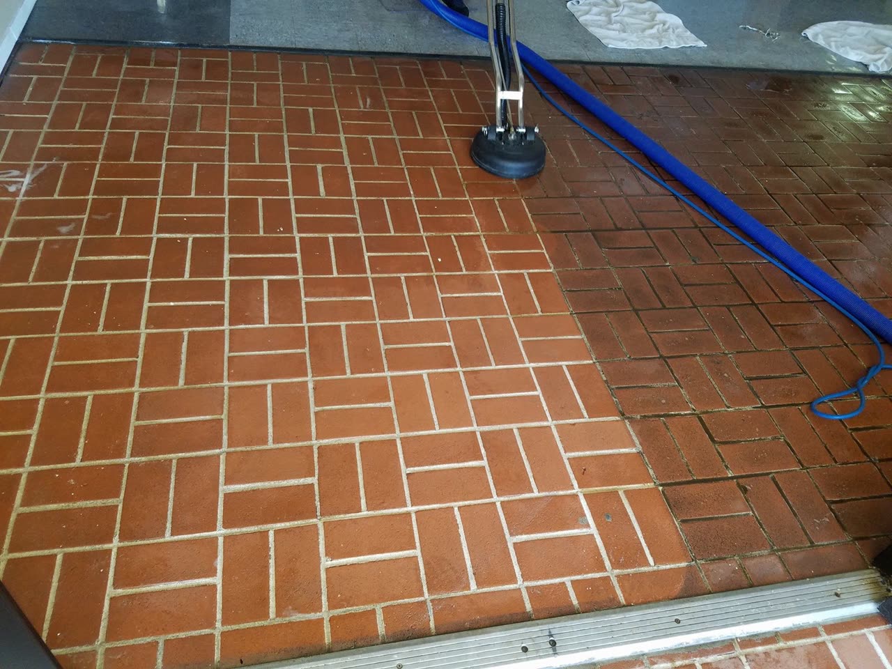 Brick tile floor, half still dirty and half cleaned